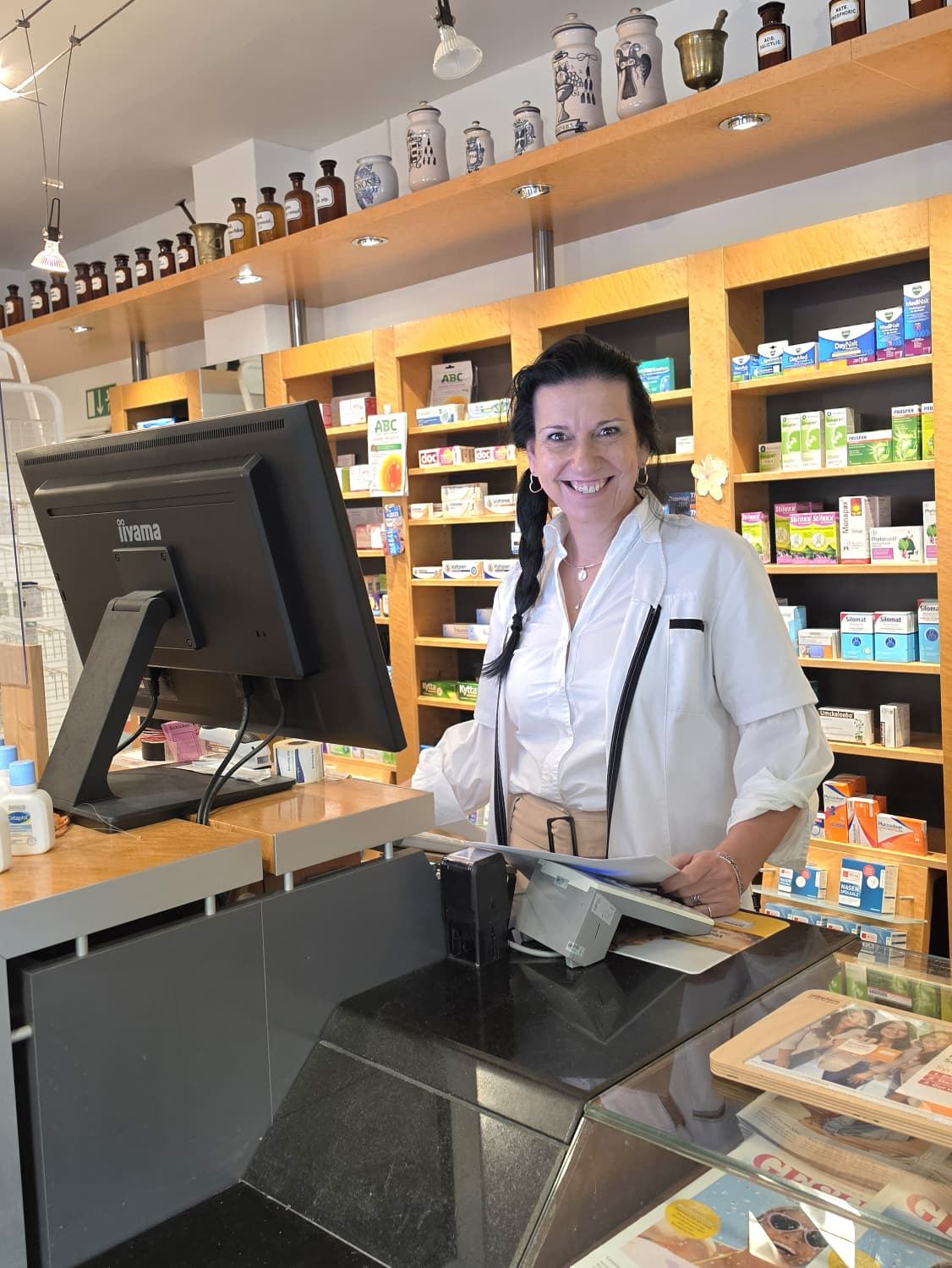 Lächelnde Mitarbeiterin am Tresen der Semmelweis-Apotheke
